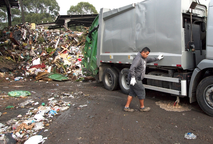 Caminhão com resíduos orgânicos de estabelecimento comercial libera líquido produzido durante o transporte, enquanto funcionário observa