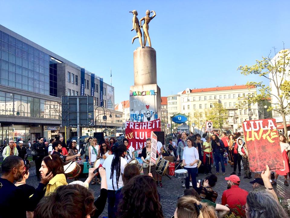 Em Berlim, dezenas de pessoas estão nas ruas denunciando a prisão política de Lula, no dia que completa um ano da condenação sem provas do ex-presidente. #LulaLivre ‬